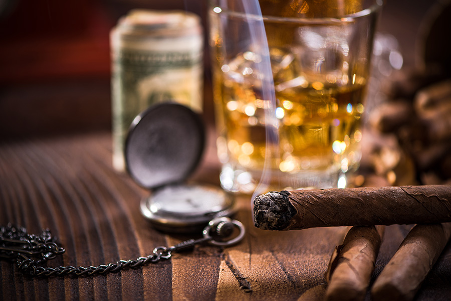 Kubanische Zigarre mit einem Glas Whiskey on the rocks, daneben eine antike Taschenuhr